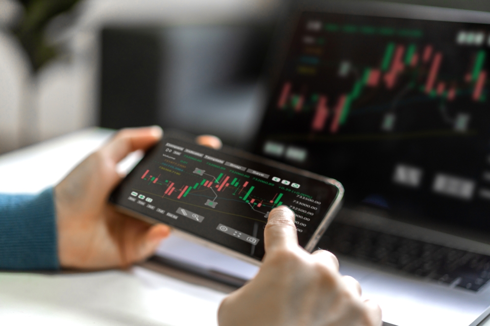 Successful,Of,Trader,Use,Phone,And,Laptop,Trading,Stock,Exchange
